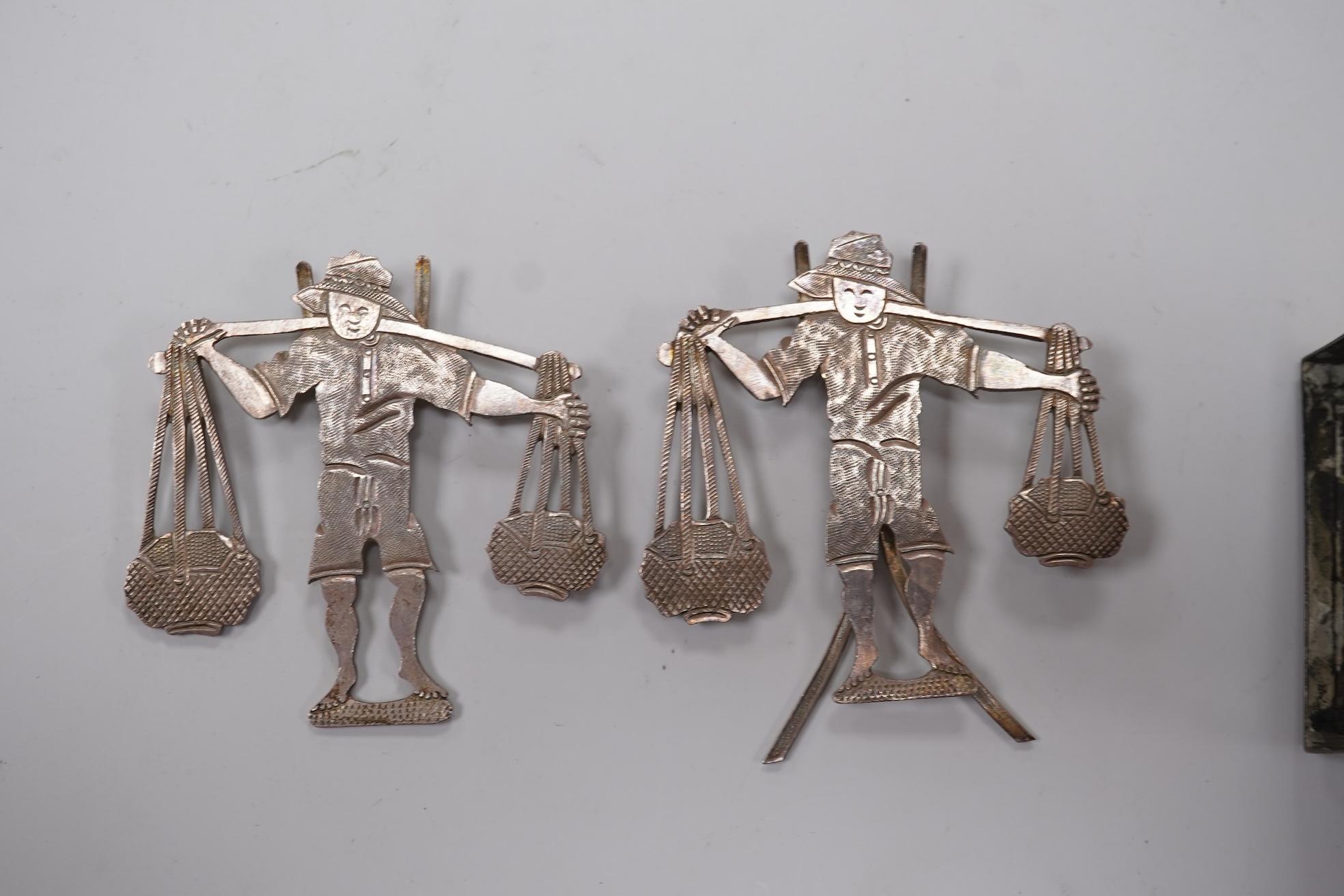 A Chinese Export white metal matchbox holder, with Chinese character mark stamp, embossed and engraved with dragon and prunus, 60mm and a pair of white metal figural menu holders, unmarked.